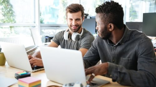 Profissionais de TI em coworking utilizando notebooks, representando colaboração, tecnologia e opensource software livre