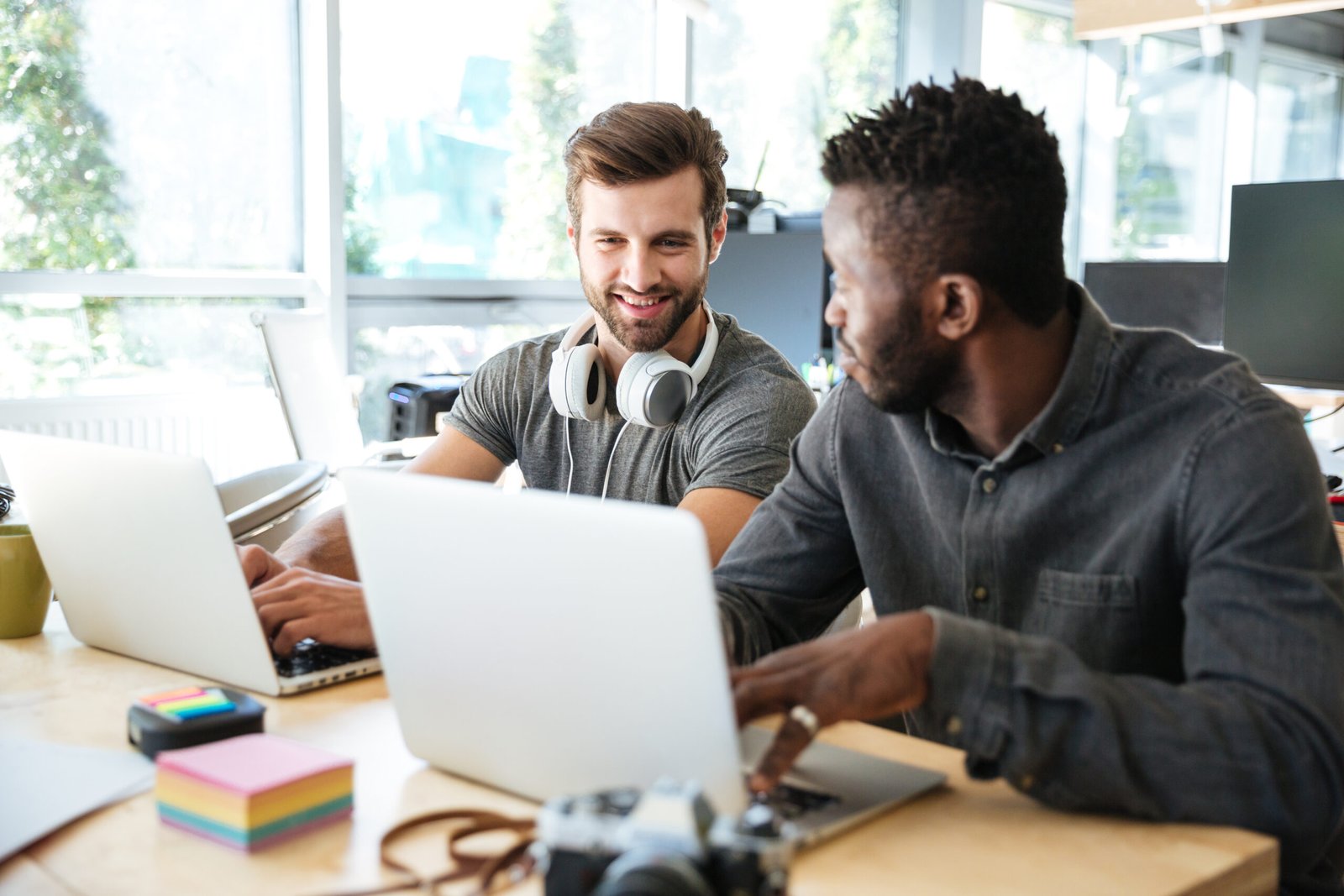 Profissionais de TI em coworking utilizando notebooks, representando colaboração, tecnologia e opensource software livre